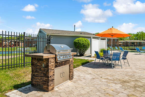 A patio with a grill and chairs is set up.