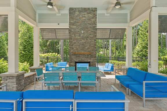 A patio with a stone fireplace and blue couches.