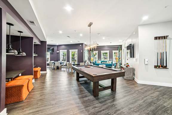 A room with a pool table and a bar area.