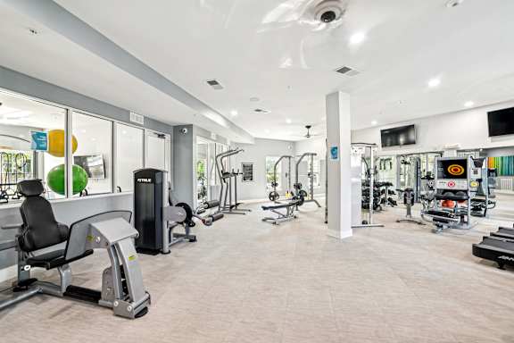 A gym with a variety of equipment including treadmills, weights, and exercise machines.