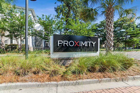 A sign that says Proximity is in front of some trees.