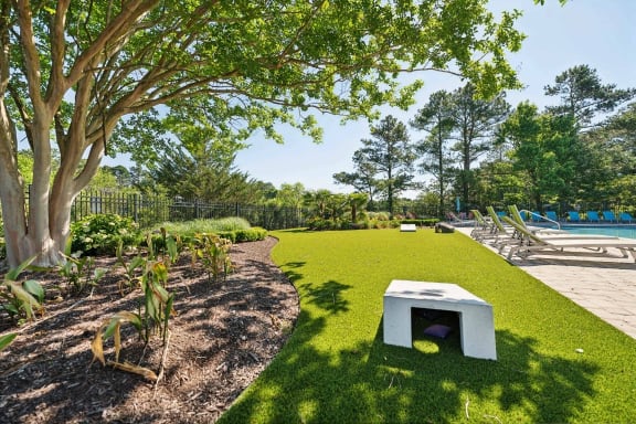 A white dog house sits on a green lawn. at The Courtyards of Chanticleer, Virginia Beach, VA