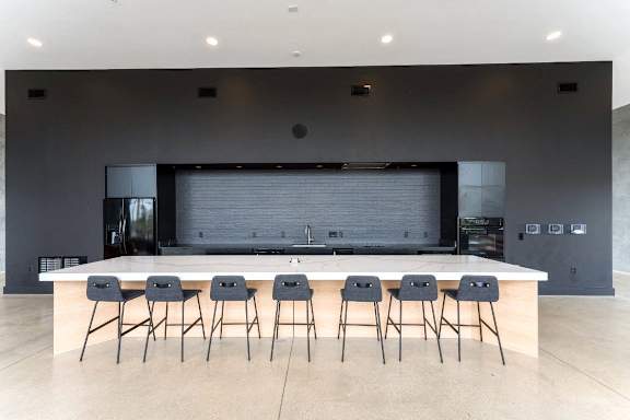 a large kitchen with a bar and chairs in front of it at South Falls Tower, Richmond, VA, 23224
