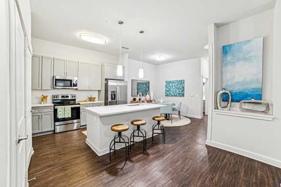 A kitchen with a white island and wooden floors.