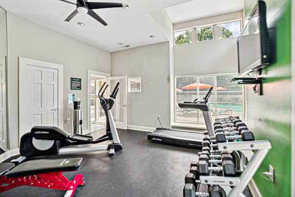 A home gym with a treadmill, elliptical trainer, and dumbbells.