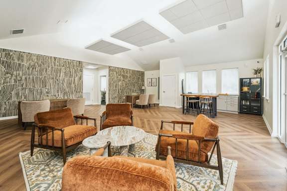 A living room with a patterned wallpaper and a variety of chairs and a coffee table.