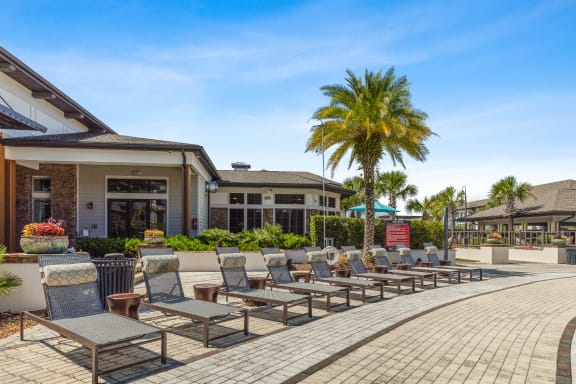 a patio with lounge chairs and palm trees in front of a building