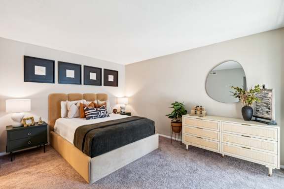 A bedroom with a large bed, a dresser, and a mirror. at Woodcreek Apartments, North Carolina