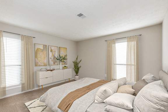 a bedroom with a large bed and two windows at Edgemont Apartments, PRG Real Estate, Greenville, 29615