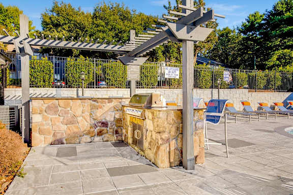 a picnic area with a grill and chairs and a stone wall at Edgemont Apartments, PRG Real Estate, Greenville, 29615