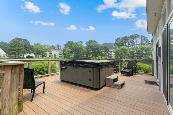 a hot tub on a deck with chairs and trees in the background
