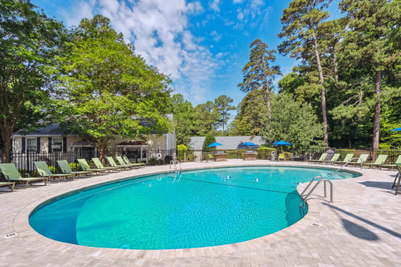 a swimming pool with lounge chairs and trees in the background at Lake Johnson Mews, North Carolina