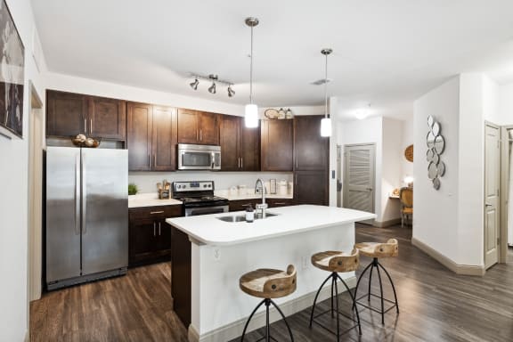 a kitchen with a large white island with three stools in front of it