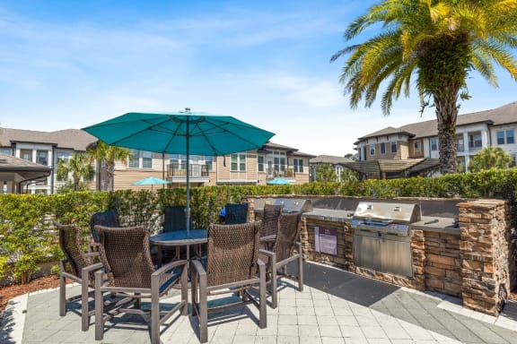 a patio with a grill and table with chairs and an umbrella