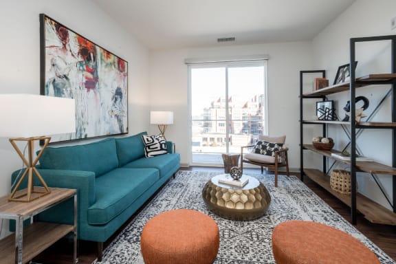 a living room with a blue couch and a large painting on the wall at East 51 At Rocketts Landing, Richmond, 23231