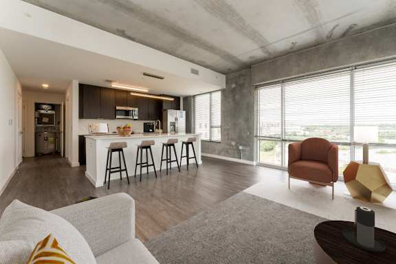 a living room with a kitchen and a large window at South Falls Tower, Richmond, VA, 23224