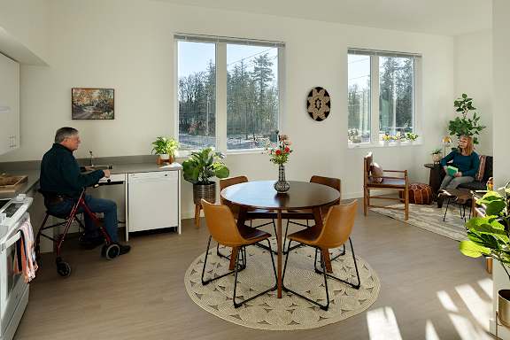 A man in a wheelchair is sitting at a table in a kitchen.