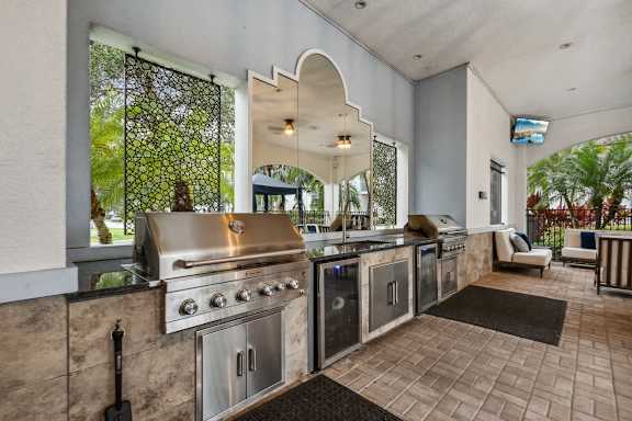 A modern outdoor kitchen with a grill and seating area.