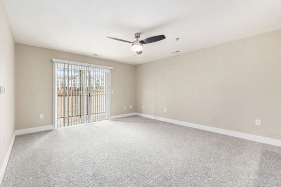 Spacious living room with ceiling fan and slider to balcony at Eagle Ridge Apartment Homes,  Michigan
