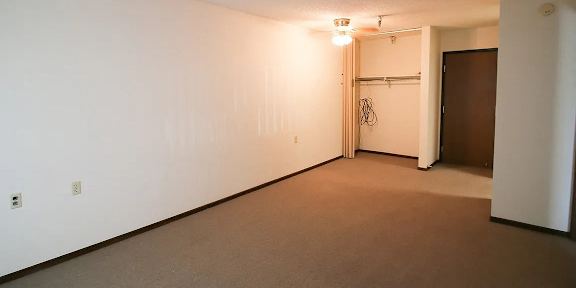 A room with a carpeted floor and a door on the right side.