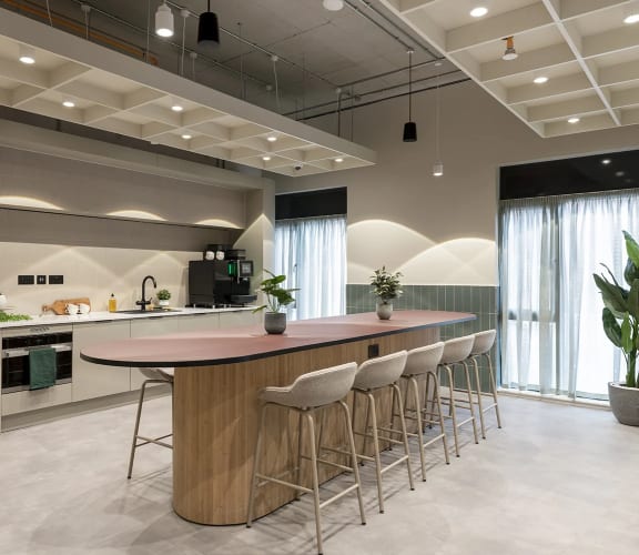 a kitchen with a counter and chairs in a lobby