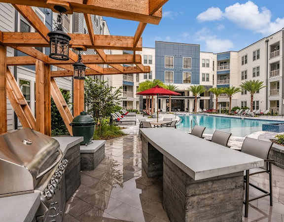 Modern BBQ grill with seating by resort-style swimming pool in Orlando, FL apartments for rent