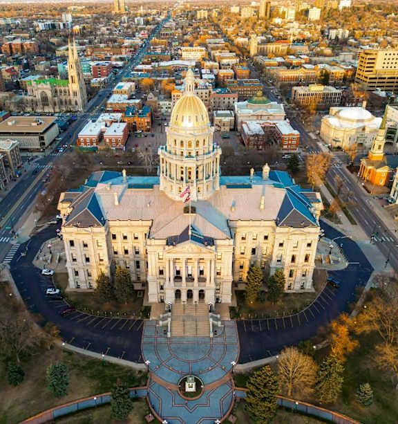 An aerial view of a large, ornate building with a dome, surrounded by a circular plaza and a busy cityscape in the background.
