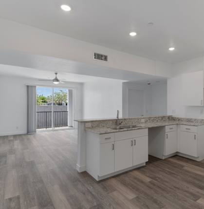 A spacious kitchen with white cabinets and a marble countertop.