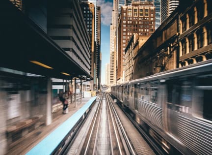 a view of the train tracks in a city with a blue train