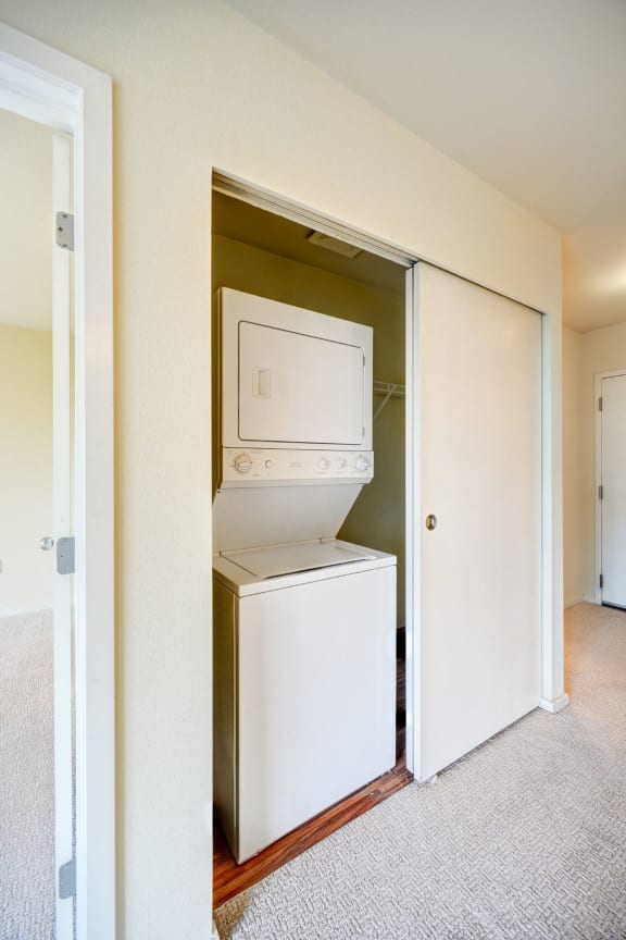 A white dryer is in a small closet.