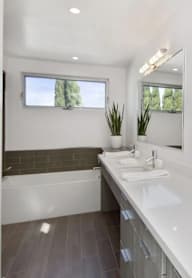 A white bathroom with a large mirror and a white sink.