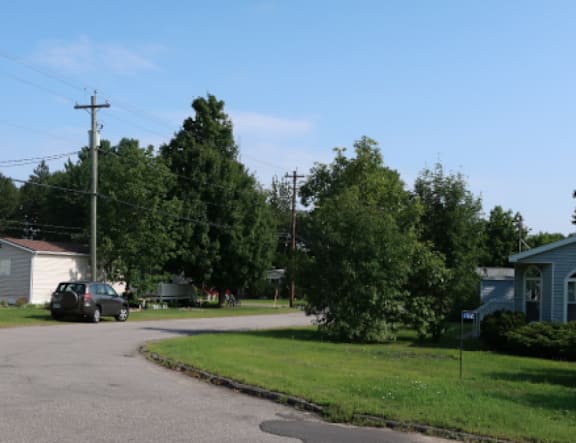 A residential street with houses and a car parked on the side.