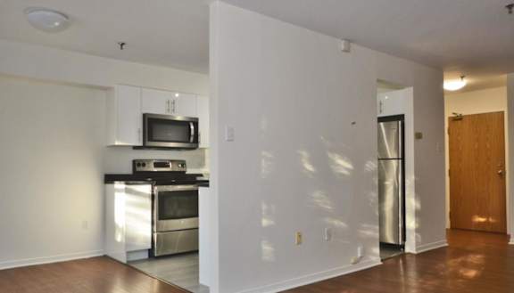 A modern kitchen with a stainless steel refrigerator and wooden flooring.
