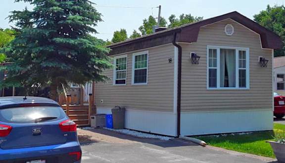 A tan building with white trim and a blue vehicle in front of it