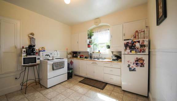 A modern kitchen with a stainless steel refrigerator and wooden flooring.