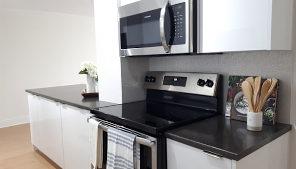A modern kitchen with a stainless steel refrigerator and wooden flooring.