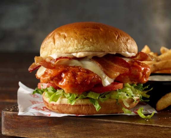 a chicken sandwich and fries on a wooden board