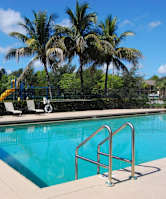 a swimming pool with chairs and palm trees