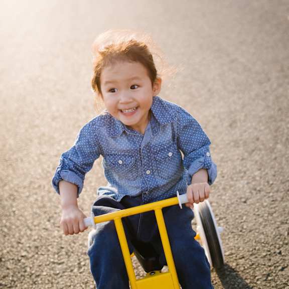 a little girl riding a tricycle down the road