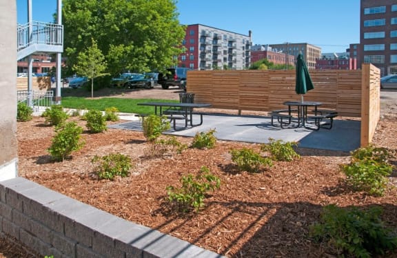 a large mulched garden with picnic tables and a patio umbrella