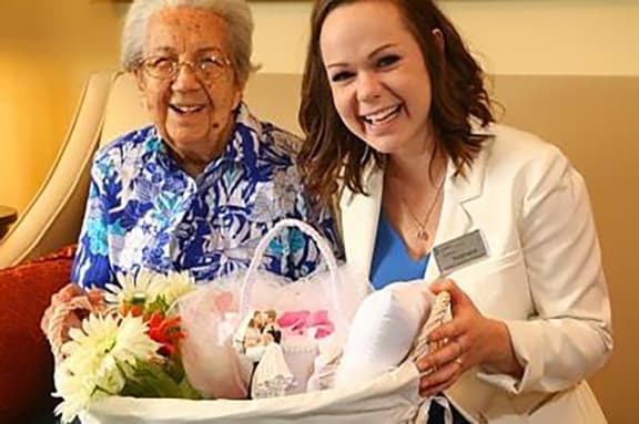 a woman holding a basket of flowers next to an older woman