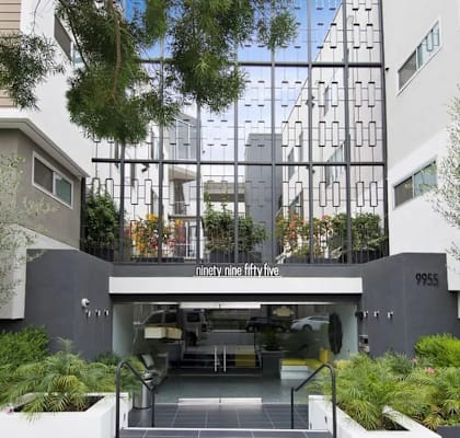 A modern building with a glass entrance and a sign that reads "ninety five fifty five.".