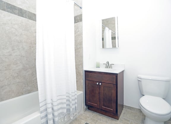 Bathroom with wooden cabinets and light grey tiles and white walls