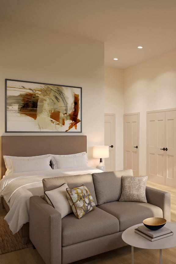 A modern bedroom with a large bed and a grey couch.