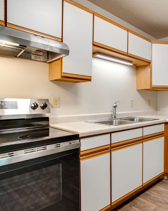 an empty kitchen with white cabinets and stainless steel appliances
