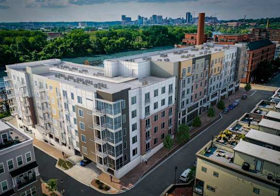 A modern apartment building is situated on a street with cars parked on the side.