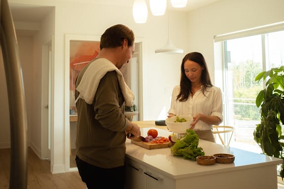 A man and woman are preparing food in a kitchen.