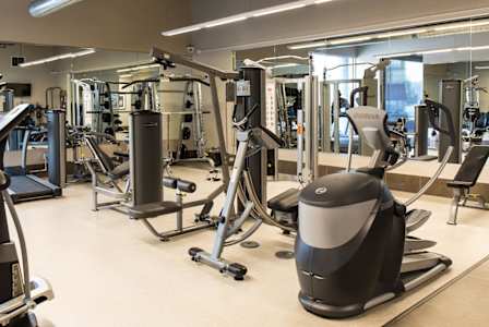 A gym with a variety of equipment including treadmills, weights, and exercise machines.