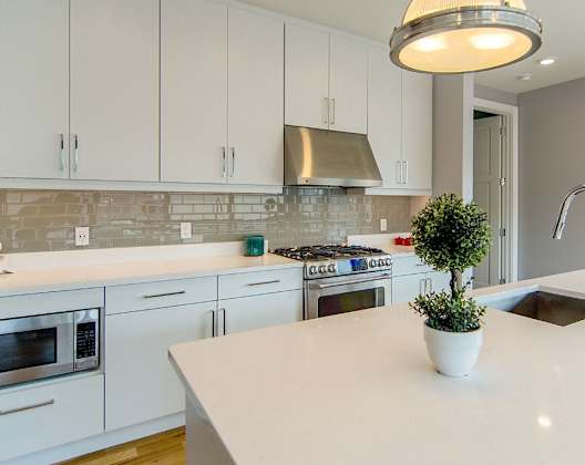 A kitchen with white cabinets and a white countertop.