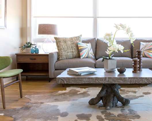 A living room with a grey couch, a green chair, and a cowhide rug.